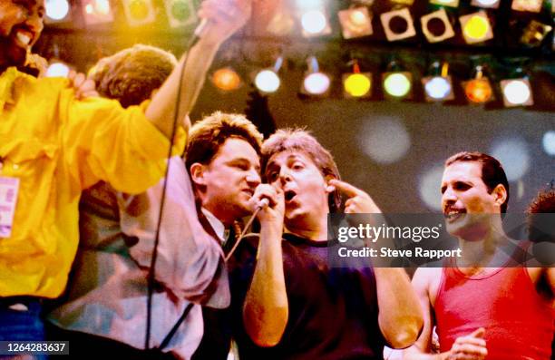 View of musicians including, from third left, Bono, Paul McCartney, and Freddie Mercury as they perform onstage during the Live Aid benefit concert,...