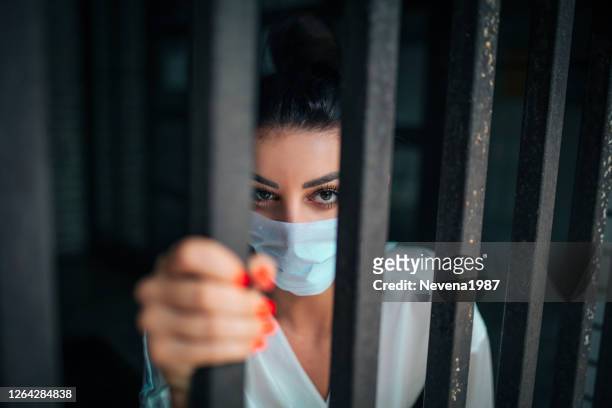 mulher com uma máscara facial olhando para fora da janela - women in prison - fotografias e filmes do acervo