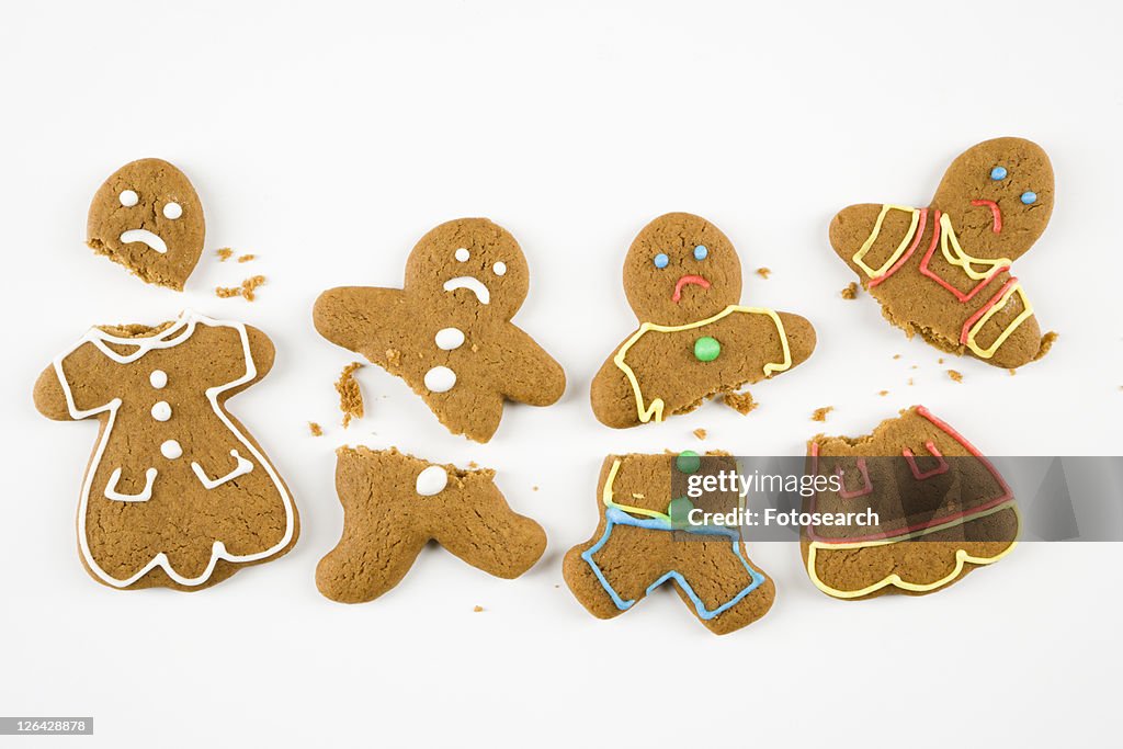 Four frowning male and female gingerbread cookies broken into pieces.