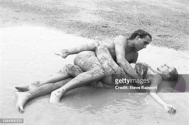English New Wave and Synth Pop musician Martin Kemp. Of the group Spandau Ballet, lies on a beach with an unidentified actress, as they film the...