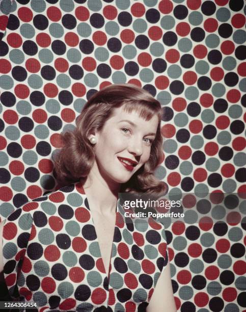 Canadian actress Lois Maxwell posed wearing a polka dot dress against a matching polka dot background in July 1952.