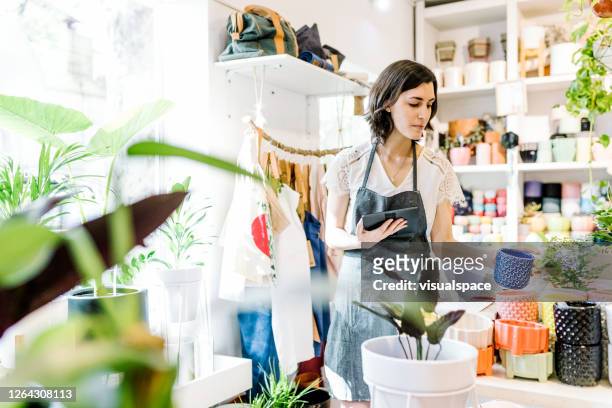 flower shop worker using digital tablet - gift shop interior stock pictures, royalty-free photos & images