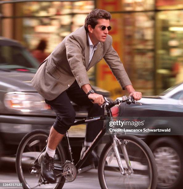 John Kennedy, Jr. Shows a little leg while he bicycles on 7th ave and 56th st. Late today thru rush hour traffic.