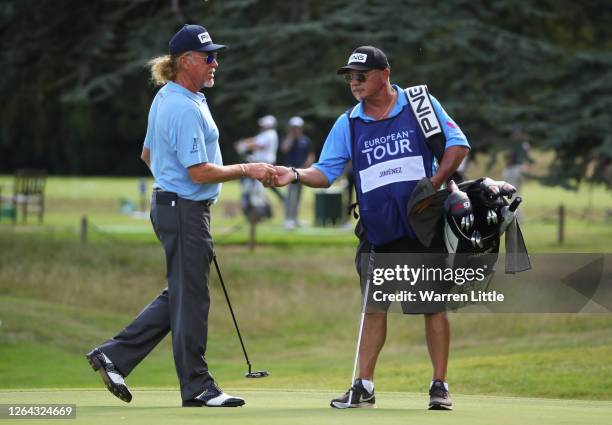 Miguel Angel Jimenez of Spain hands his golf ball on the 18th hole with caddie Kyle Roadley during Day One of the English Championship at Hanbury...