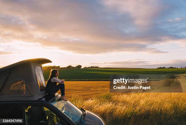 woman sitting on roof of campervan at sunset - adventure sunset stock pictures, royalty-free photos & images