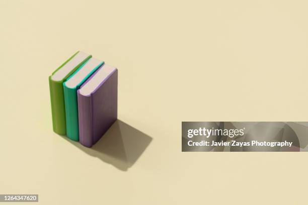 three books on a pastel colored background - enzyklopädie stock-fotos und bilder