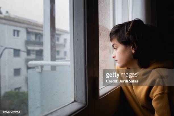 boy at the window - winter sadness stock pictures, royalty-free photos & images