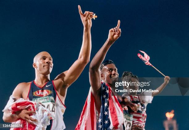 Mark Crear of the USA holds daughter Ebony and Allen Johnson of the USA holds his daughter Christine as they complete a victory lap after winning...