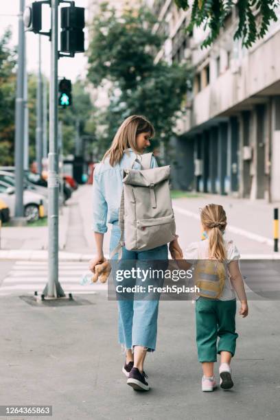 first day of school: a cute first grader going to school with her mom - family from behind stock pictures, royalty-free photos & images