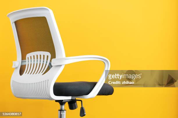 part of office chair in front of yellow background - bürostuhl stock-fotos und bilder