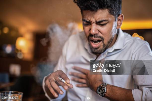 junger mann hustet vor dem rauchen einer zigarette. - smoke heart stock-fotos und bilder