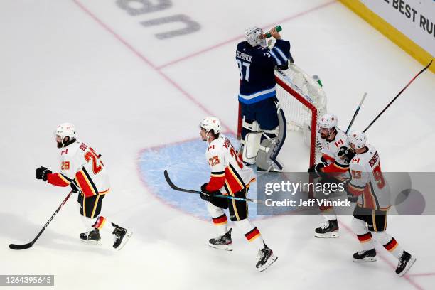 Dillon Dube of the Calgary Flames celebrates with his teammates after scoring a goal on Connor Hellebuyck of the Winnipeg Jets during the first...