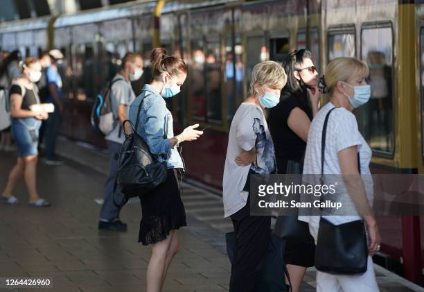 Commuters wearing protective face masks board a train during the novel coronavirus pandemic on August 07, 2020 in Berlin, Germany. Coronavirus...