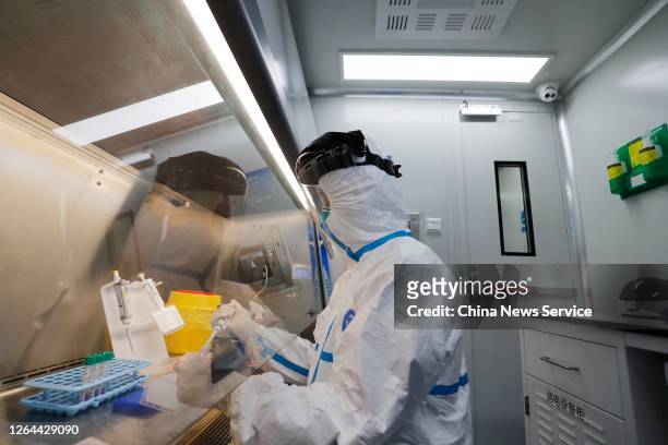 Customs officer wearing a protective suit works in a mobile COVID-19 testing laboratory at Shanghai Pudong International Airport on August 7, 2020 in...