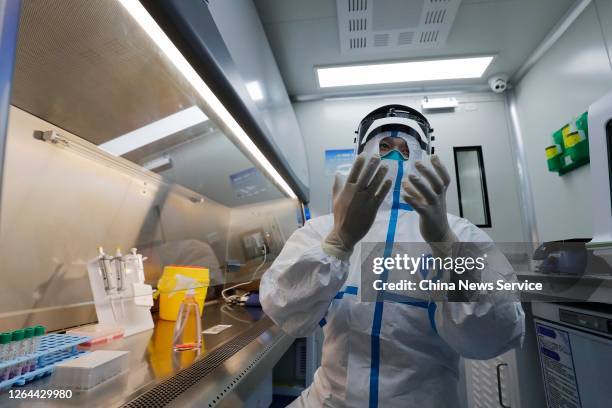 Customs officer wearing a protective suit works in a mobile COVID-19 testing laboratory at Shanghai Pudong International Airport on August 7, 2020 in...