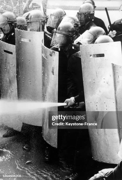 Des policiers derrière leurs boucliers aspergent les manifestants de gaz lacrymogène, à Tokyo, Japon en janvier 1968.