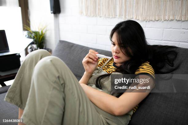 asian young woman looking at pregnancy test with disappointed expression - infertility stock pictures, royalty-free photos & images