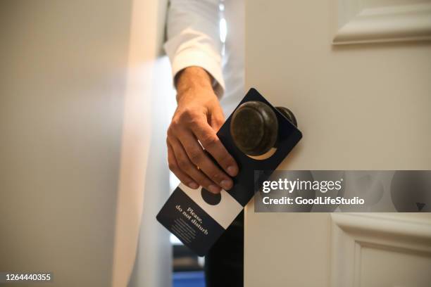 man putting a do not disturb sign - do not disturb sign stock pictures, royalty-free photos & images