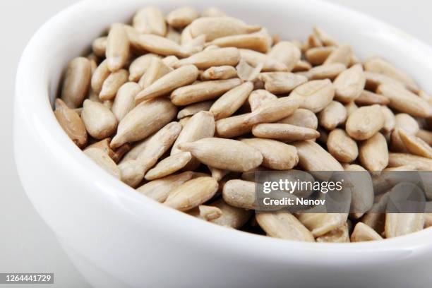 close-up of peeled sunflower seed isolated on white background - sonnenblumenkerne stock-fotos und bilder