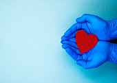 red heart in hands in blue medical gloves on a blue background. background for the day of the medic
