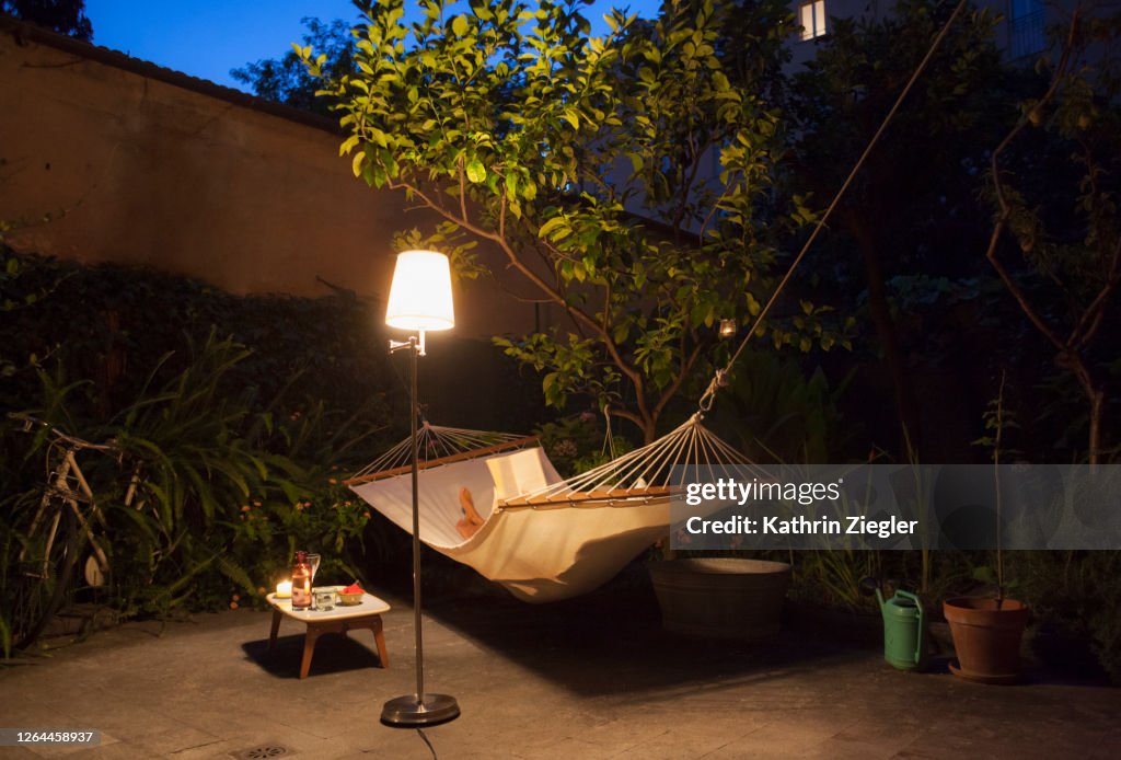 Woman reading in the hammock in garden at night