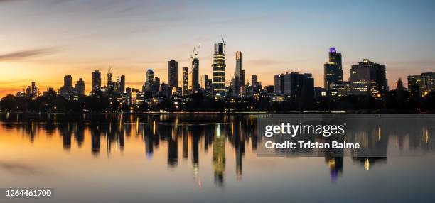 the reflections of the melbourne city skyline at dusk in the still water of albert park lake - screen saver stock-fotos und bilder