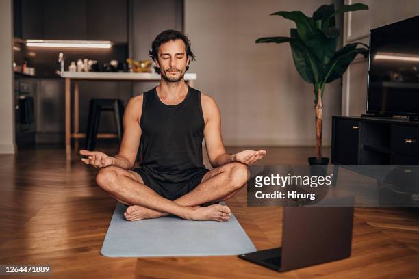 mann meditiert im wohnzimmer - yoga stock-fotos und bilder