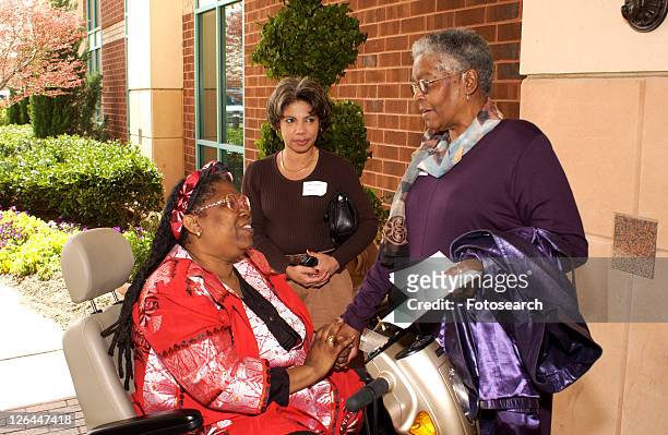 three women talking and comparing notes during break at a disability action conference. - multiple sclerosis fotografías e imágenes de stock