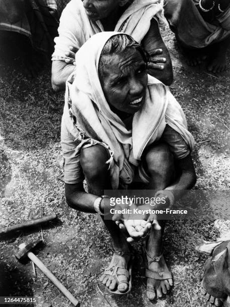 Dans une rue d'une ville indienne, une vieille femme tend la main pour manger, en Inde le 29 mars 1968.