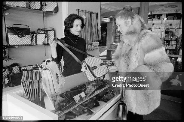 At an unspecified shop in the Watergate complex, a clerk shows a Gucci handbag to a customer dressed in a fur coat, Washington DC, January 3, 1979.