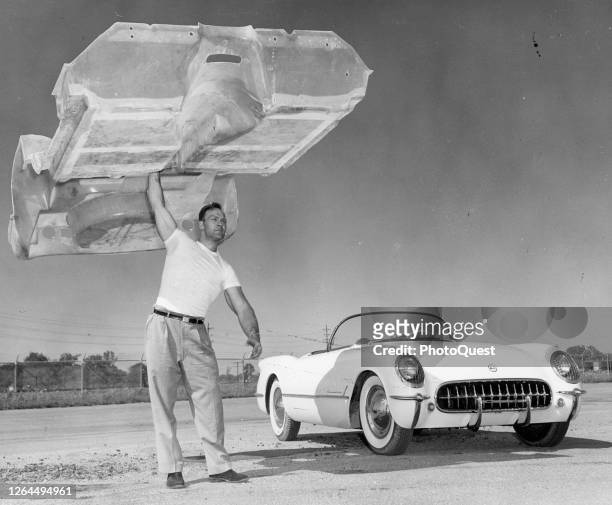An unidentified man holds aloft the lightweight, fiberglass body of Chevrolet Corvette sports car, Detroit, Michigan, 1958.