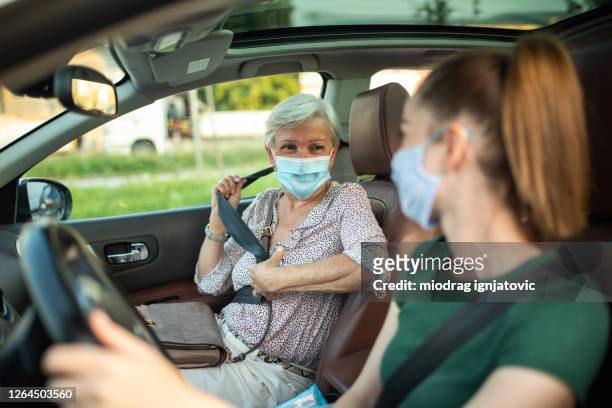 lächelnde frauen mit schützenden gesichtsmasken im ride-sharing-auto - carpool stock-fotos und bilder