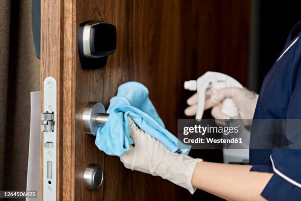 close-up of chambermaid wiping doorknob in hotel - handle stock-fotos und bilder