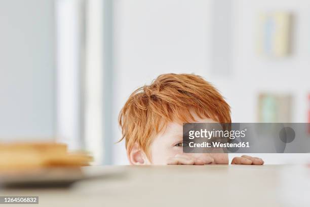 portrait of a cute boy at home looking at plate on table - greed stockfoto's en -beelden