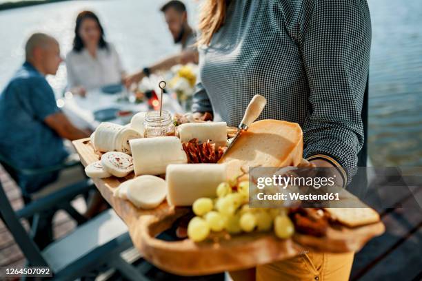 friends having dinner with a cheese platter at a lake - cheese platter stock-fotos und bilder