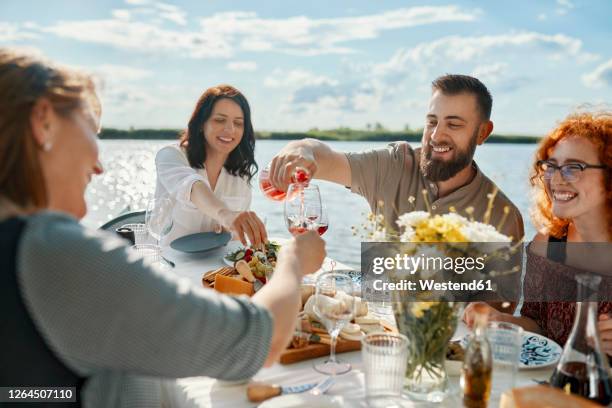 friends having dinner at a lake drinking wine - outdoor dining stock pictures, royalty-free photos & images