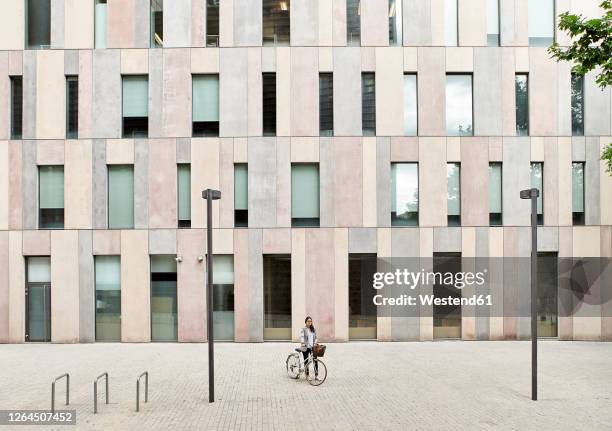 businesswoman standing with bicycle on street outside office building - side by side stock pictures, royalty-free photos & images