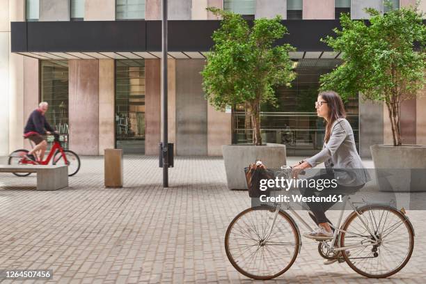 businesswoman commuting on bicycle in city - bicycle basket stock pictures, royalty-free photos & images
