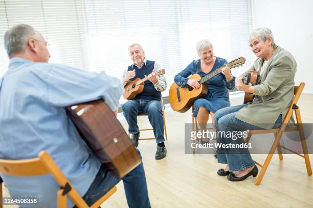 seniors in retirement home attending guitar class, making music - music therapy stock pictures, royalty-free photos & images
