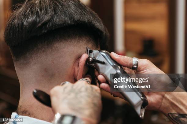 barber's hands using electric razor on man at hair salon - cutting hair stock pictures, royalty-free photos & images