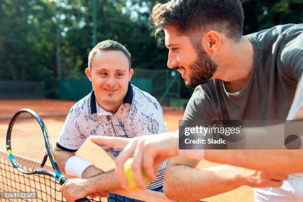 young man with down syndrome on tennis court - sportsperson stock pictures, royalty-free photos & images