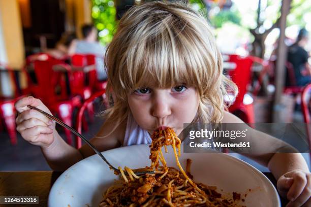 girl eating spaghetti at restaurant - restaurant kids stock-fotos und bilder