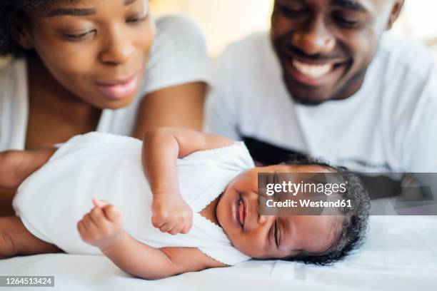 close-up of smiling parents looking at newborn daughter sleeping on bed - cute black newborn babies bildbanksfoton och bilder