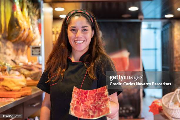 woman in uniform showing a paper full of ham slices while is facing the camera on a butcher - white butcher paper stock pictures, royalty-free photos & images