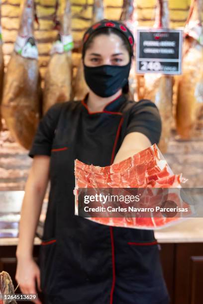 vertical photo of a woman with mask and black gloves showing a paper full of ham slices while is facing the camera on a butcher - white butcher paper stock pictures, royalty-free photos & images