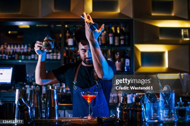 male bartender making cocktails on bar counter in pub at night - bartender mixing drinks stock-fotos und bilder