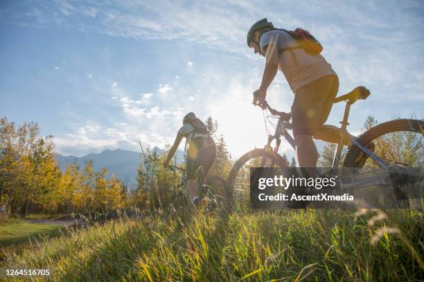 mountain biker rides along grassy path, in autumn - bicycle trail outdoor sports stock pictures, royalty-free photos & images