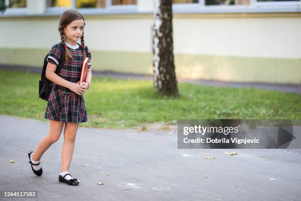 het meisje dat van de school onderaan de straat loopt - schoolgirl stockfoto's en -beelden