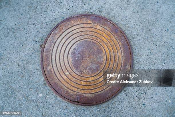 rural or urban storm sewer manhole cover on the asphalt surface - マンホール ストックフォトと画像