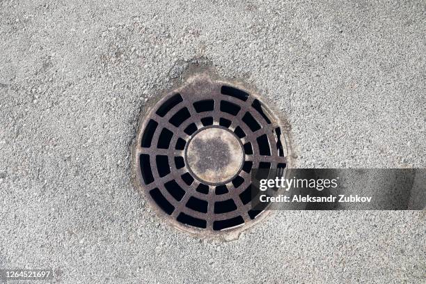 rural or urban storm sewer manhole cover on the asphalt surface - drainage stock pictures, royalty-free photos & images